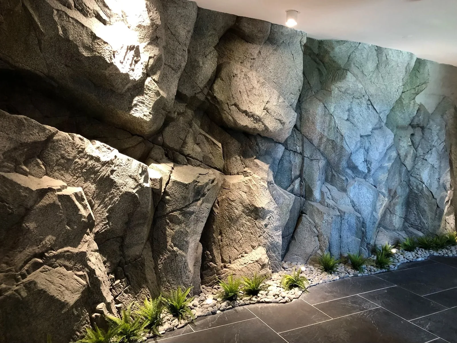 Pared decorativa con rocas esculpidas e iluminación, realizada por el maestro de Familia Studio